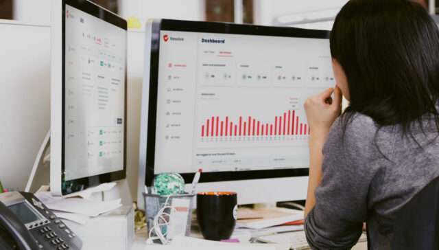 woman-looking-at-dual-imac-screens-grc-software-reporting